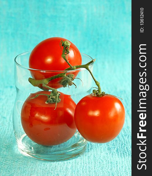 fresh tomatoes in glass on blue background