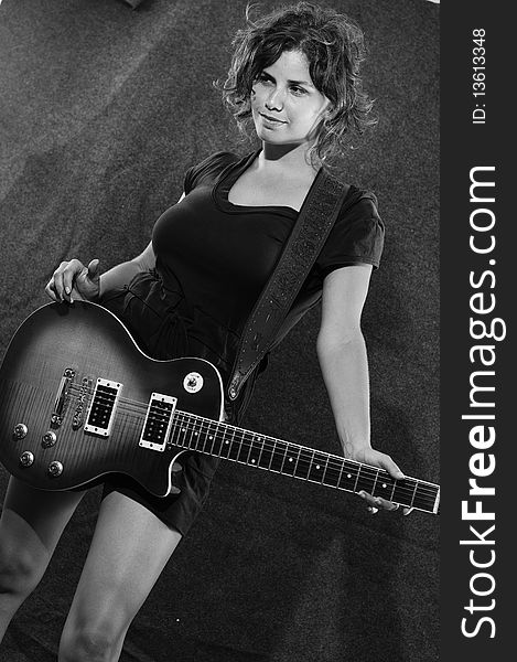 Portrait of young woman holding electric guitar in black and white. Portrait of young woman holding electric guitar in black and white