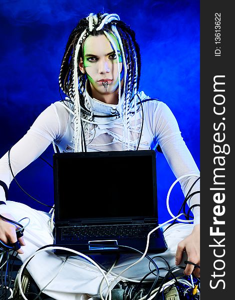 Shot of a futuristic young man sitting with a laptop and wires. Shot of a futuristic young man sitting with a laptop and wires.