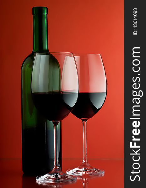 Two wineglass and bottle on a red background