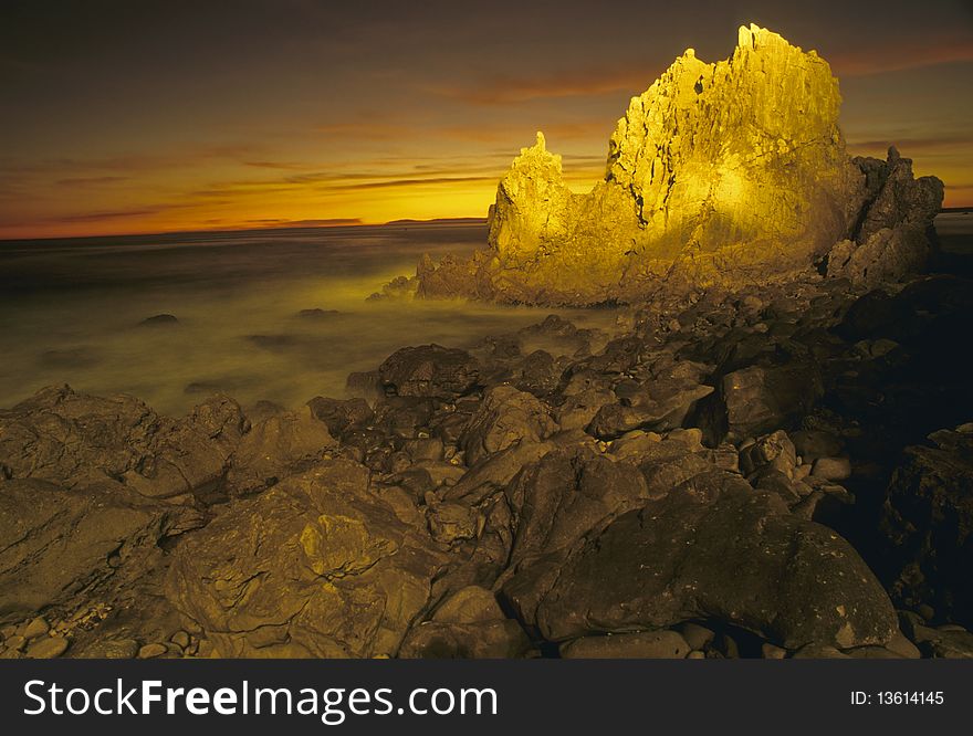 Rocky coast at sunset with rocks in foreground. Rocky coast at sunset with rocks in foreground