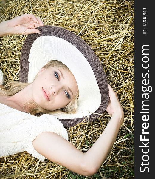 Young beautiful girl lying on the straw in the field. Young beautiful girl lying on the straw in the field