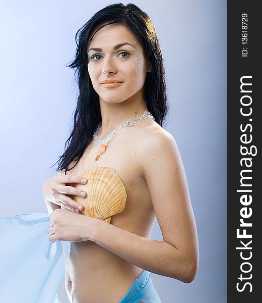 Beautiful summer girl with shell on blue background