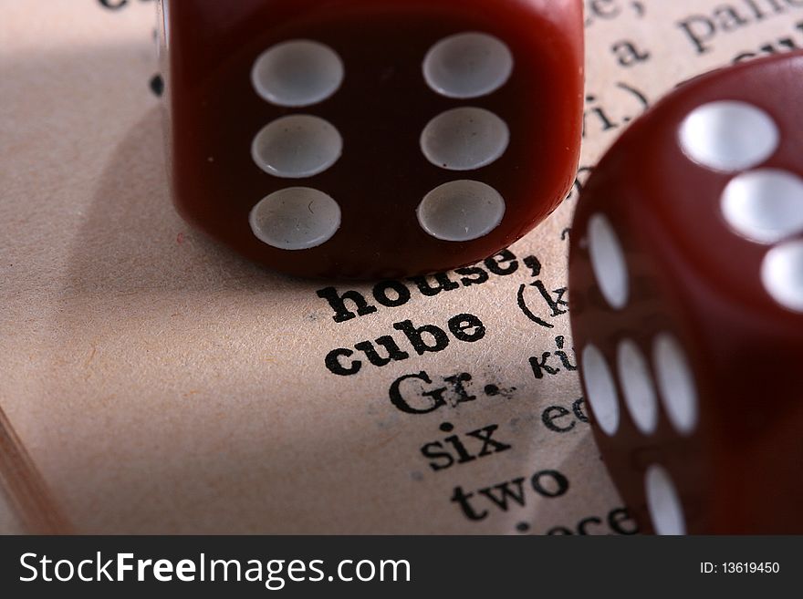 Two red cubes for gamblings against the book with a word cube.