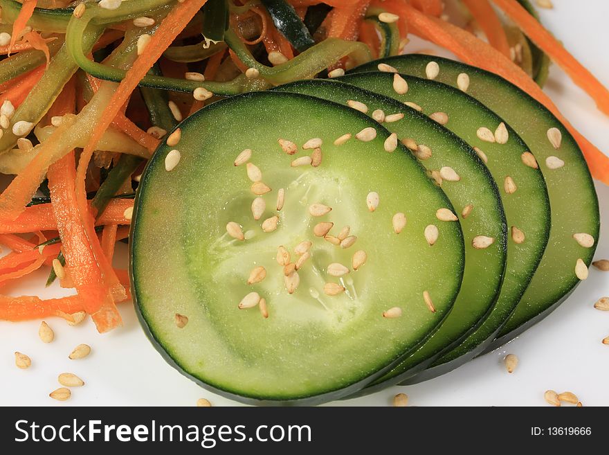 Macro photo of cucumber carrot salad presented on a white plate.
