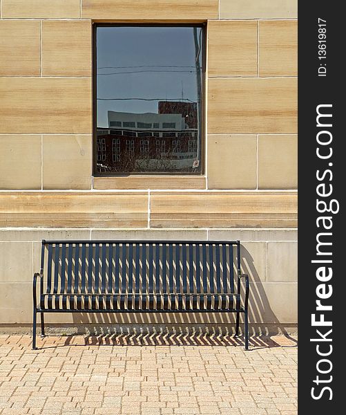 Image of a solitary bench under a window with vintage building background and interlocking ground surface. Image of a solitary bench under a window with vintage building background and interlocking ground surface.