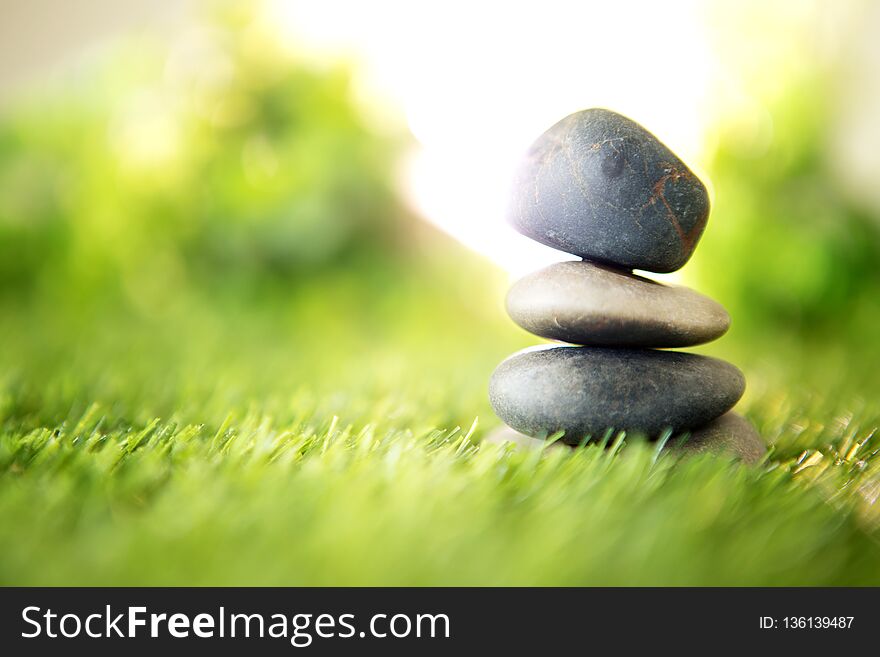 Balance with a pyramid of stone on fresh nature green grass , spa meditation or well-being with zen concept
