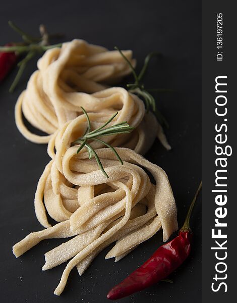 Homemade raw pasta. Italian traditional raw pasta on black background with spices. Homemade raw pasta. Italian traditional raw pasta on black background with spices