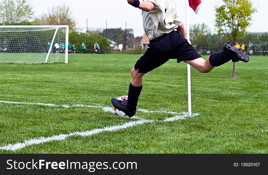 A boy kicks a soccer ball from a goal corner during a youth soccer game. A boy kicks a soccer ball from a goal corner during a youth soccer game.