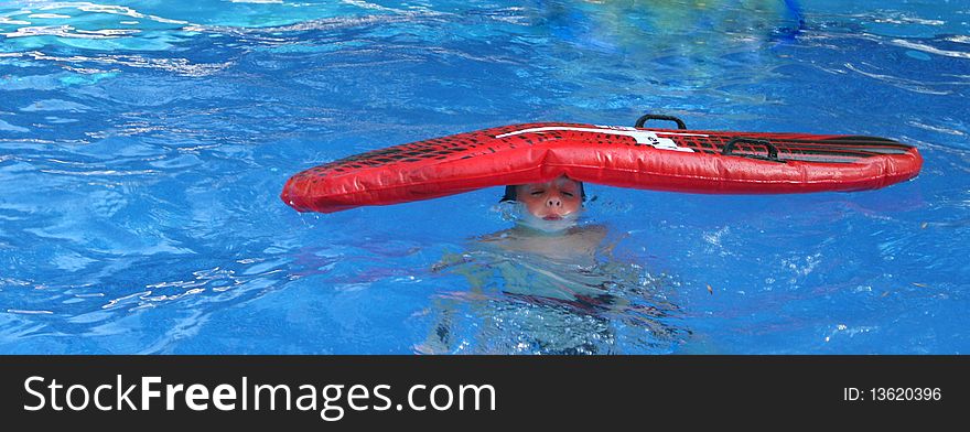 Boy in pool with an inflatable bed on his head
