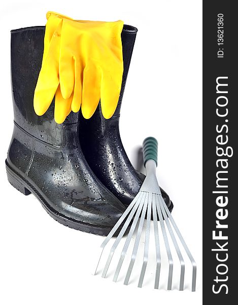 Gardening tools: rubber boots, rake and yellow  gloves