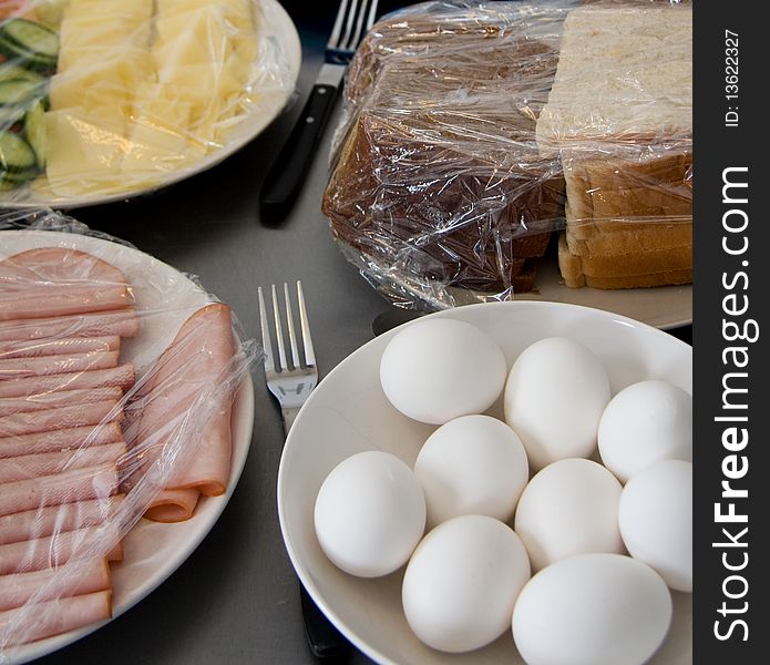 Eggs and bread and ham and cucumber and cheese covered with plastic. Eggs and bread and ham and cucumber and cheese covered with plastic.