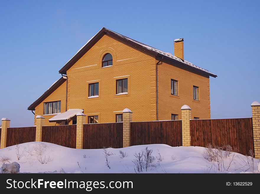 Large house in the winter against the blue sky