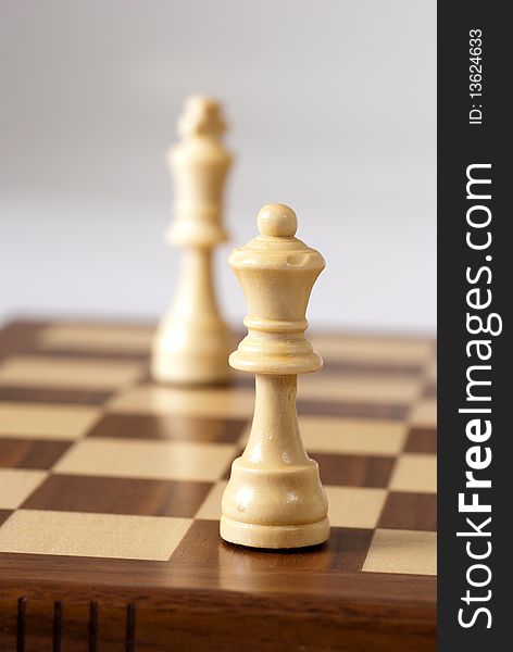 Chess pieces on a chessboard against a white background