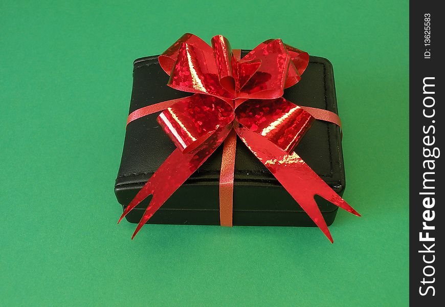 Black gift box with red ribbon isolated on green