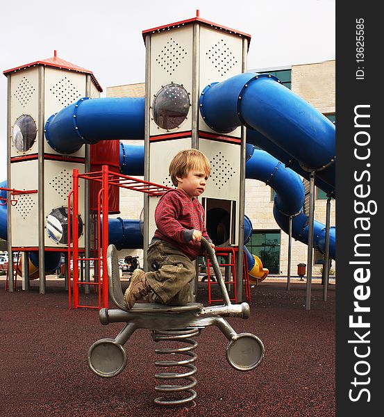 2 year old child sitting on a motorcycle on the playground