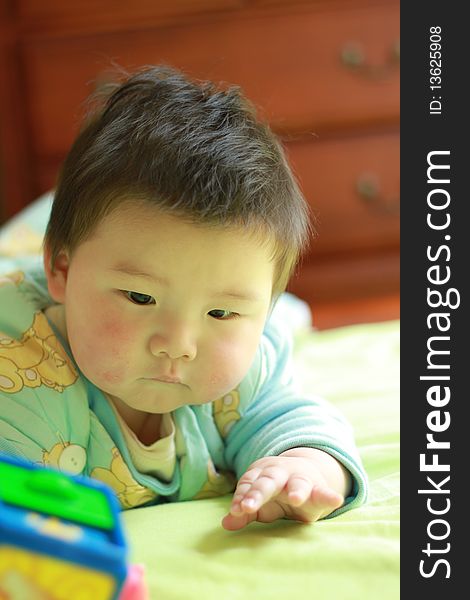 Lovely Chinese baby playing in the bed with some toys. Lovely Chinese baby playing in the bed with some toys