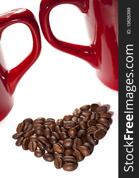 Coffee-beans heart against red cup`s handles on white backround