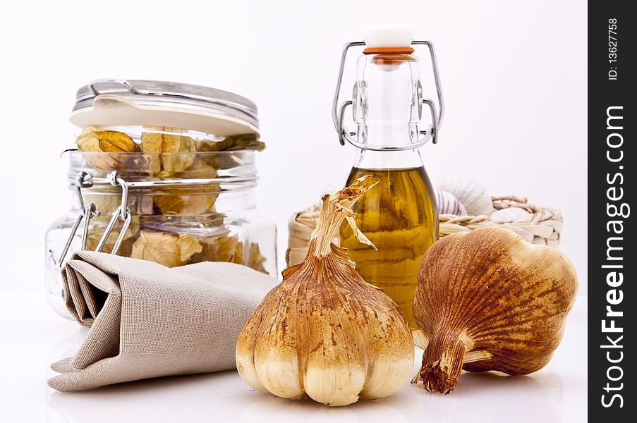 Smoked Garlic Bulbs, Olive oil and Physalis on a white background