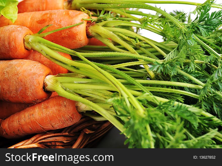 Heap of fresh carrots with leaves in basket