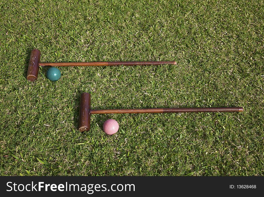 A set of croquet mallets and balls on lawn. A set of croquet mallets and balls on lawn