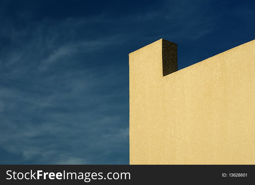 Background: yellow wall, ledge and cloudy blue sky. Background: yellow wall, ledge and cloudy blue sky