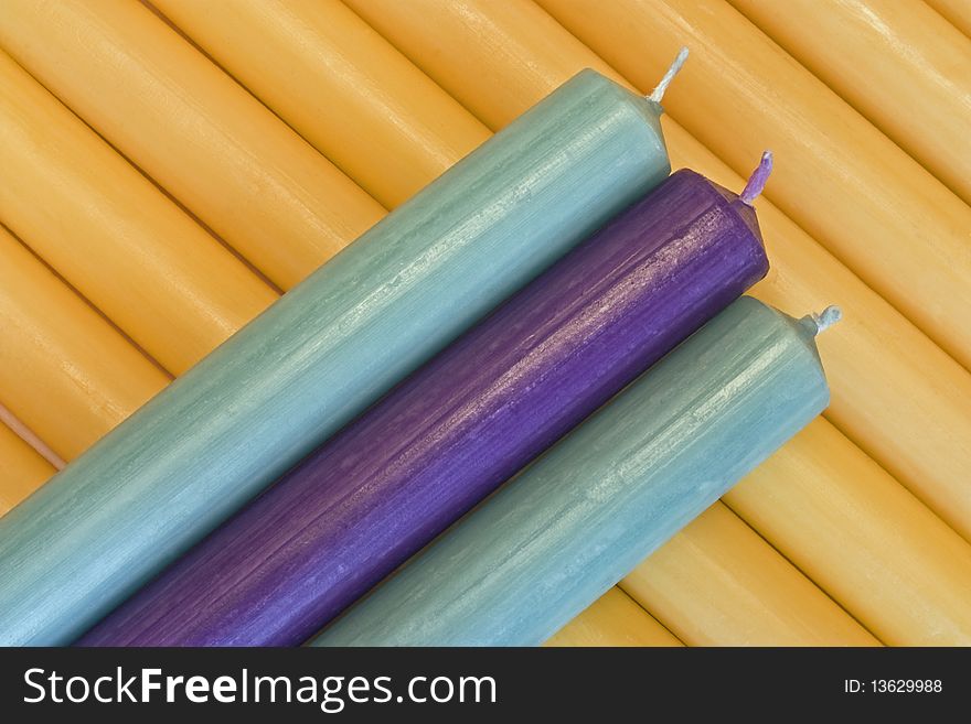 A close-up of blue, mauve and cream candles shot on the diaggonal