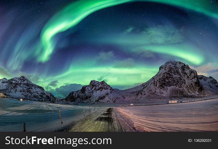 Northern lights explosion on snowy mountain range near coastline at Lofoten islands, Norway