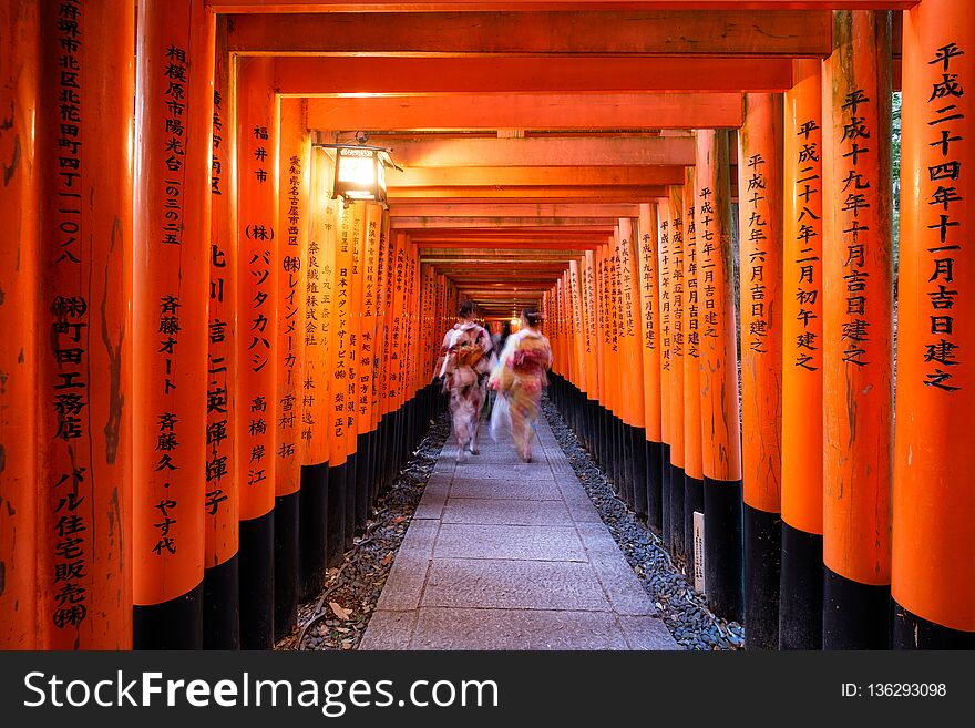 Kyoto, Japan - Nov 11 2017 : Woman dressed kimono walking in red ancient wood torii gate at Fushimi Inari