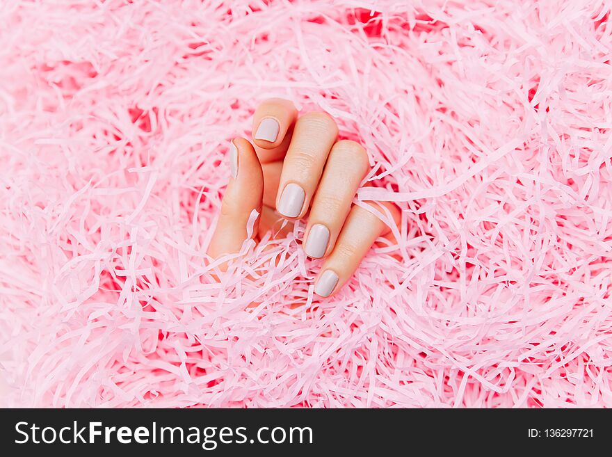 Beautiful female hands with trendy stylish manicure on pink background. Multicolored Bottles of nail polish. Top view, flat lay