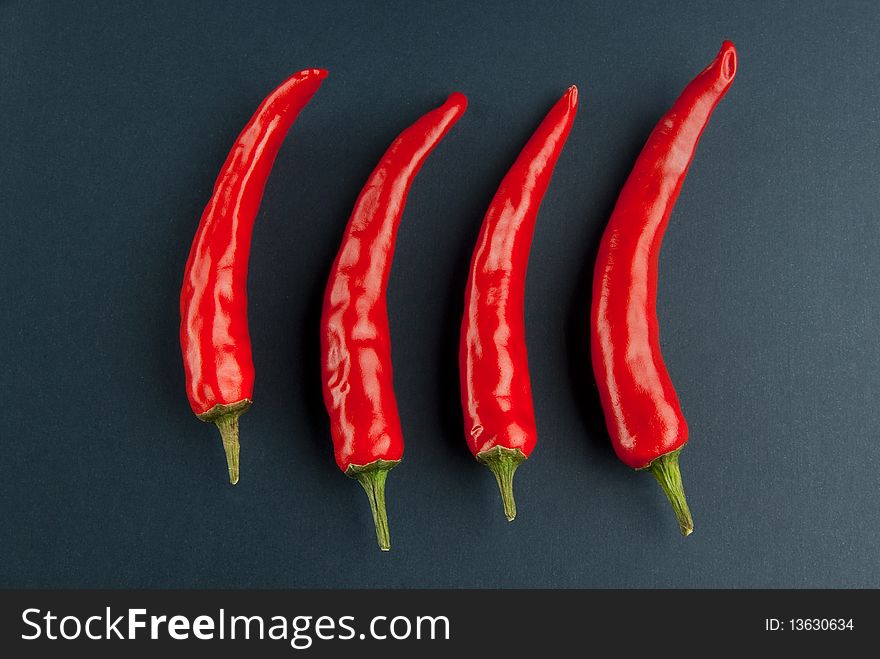 Four peppers row on the black background. Four peppers row on the black background