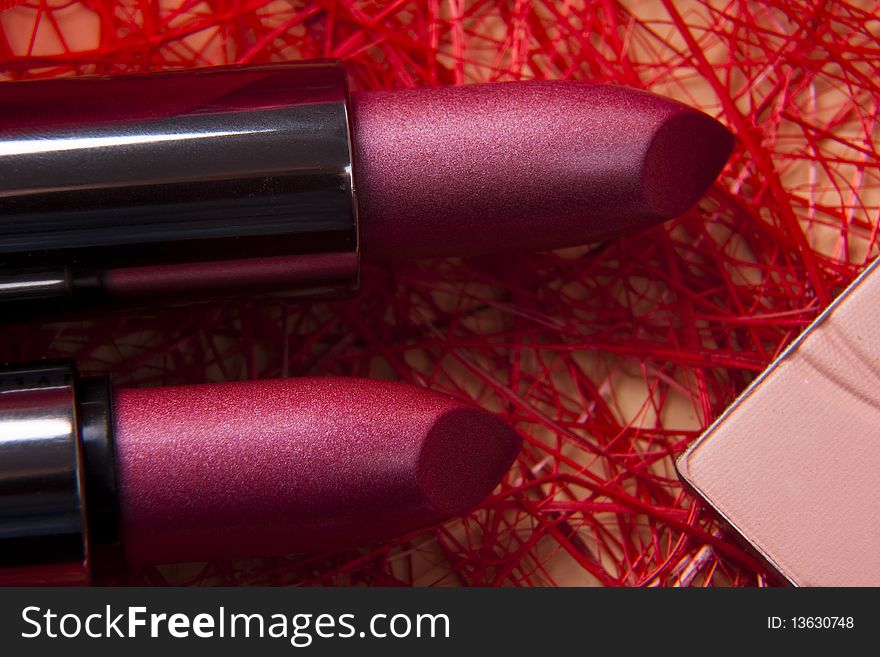 Two lipsticks and powder on red background. Two lipsticks and powder on red background