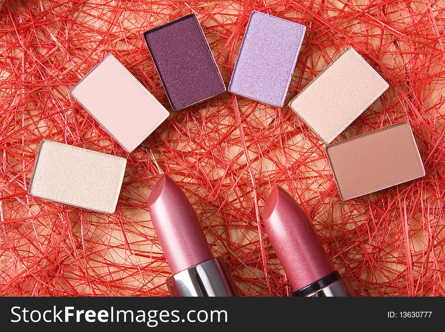 Eye shadow and lipsticks on red background.