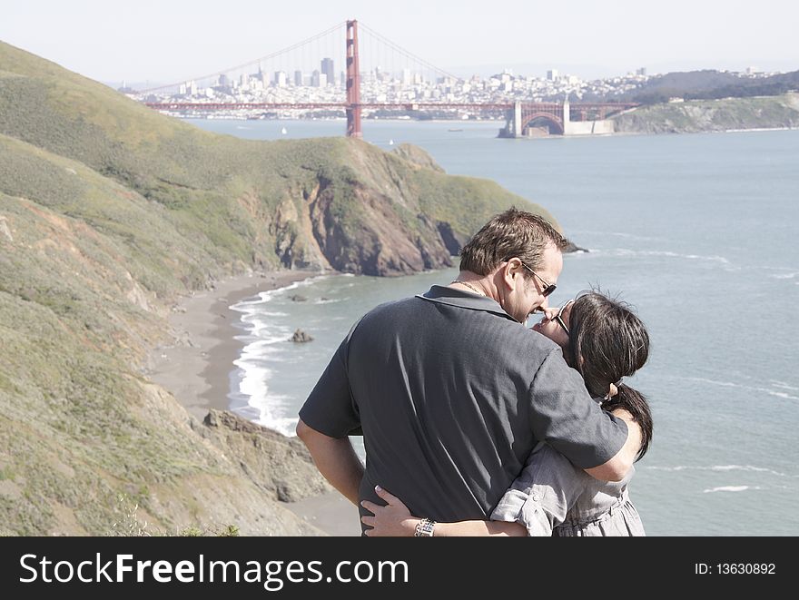 An affectionate couple on vacation enjoying the view of the Golden Gate Bridge and San Francisco's cityscape