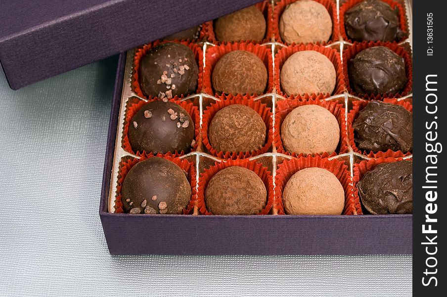 A box of chocolate truffles on light textured background. A box of chocolate truffles on light textured background