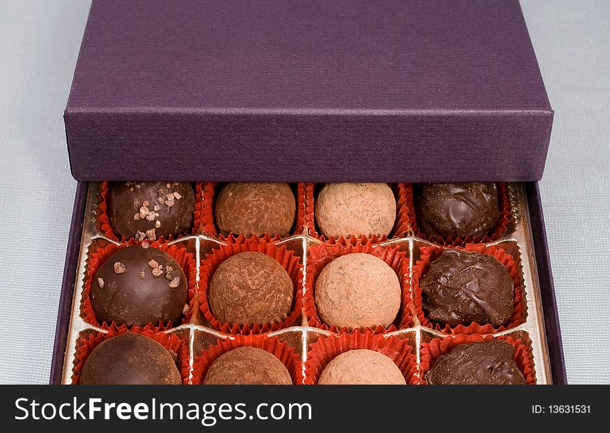 A box of chocolate truffles on light textured background. A box of chocolate truffles on light textured background