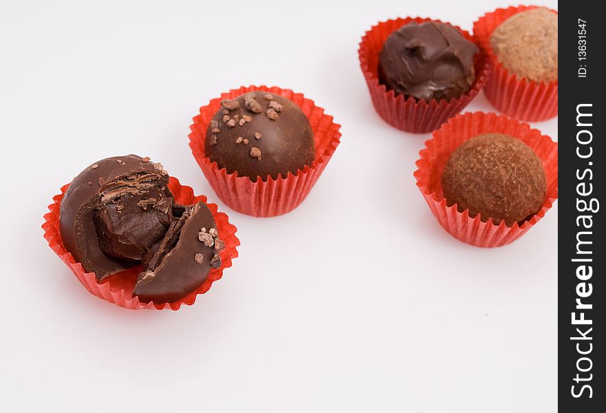 Assortment of chocolate truffles isolated on white background, focus on closest truffle in foreground