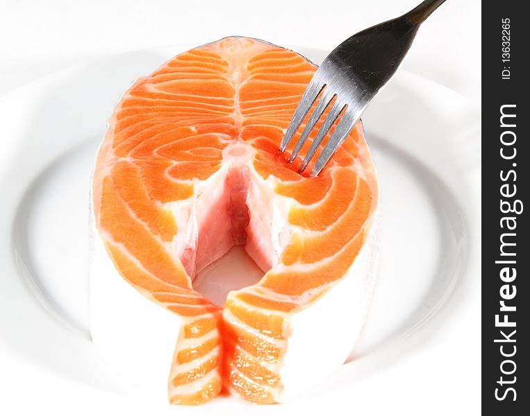 Salmon Slices pricked with a fork on white background