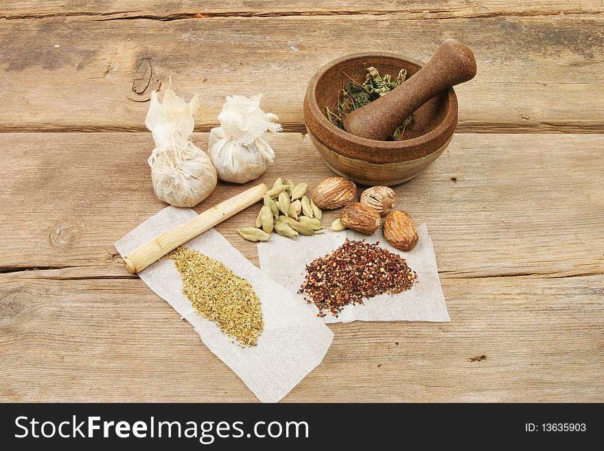 Pestle and mortar with herbs and spices on old weathered wood