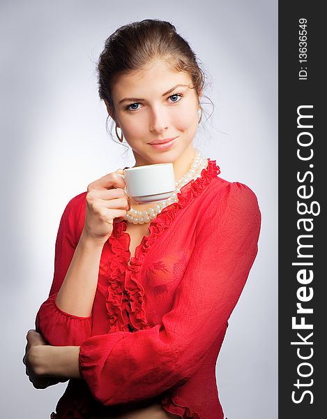 Portrait beautiful young brunette in red with a cup in his hands. Portrait beautiful young brunette in red with a cup in his hands
