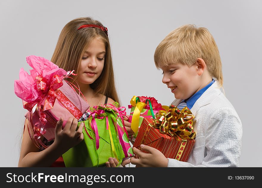 Beautiful boy and girl standing side by side with gifts in their hands. Beautiful boy and girl standing side by side with gifts in their hands
