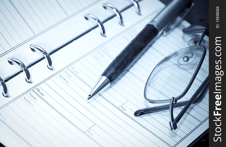 Binder, pen and glasses. blue toning