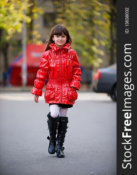Young girl in a red jacket walking along the street. Young girl in a red jacket walking along the street