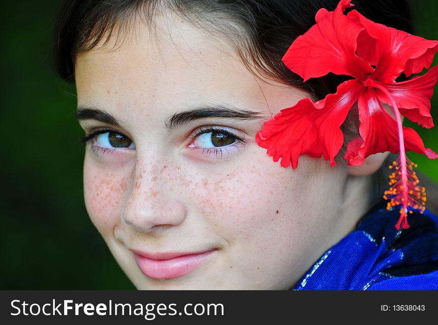 A tween girl with a red hibiscus in her hair. A tween girl with a red hibiscus in her hair.