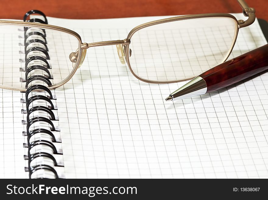 Notepad with eyeglasses and pen on the desk