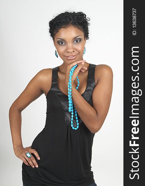 Beautiful brunette african woman wearing party clothes and accessories smiling on grey background. Beautiful brunette african woman wearing party clothes and accessories smiling on grey background