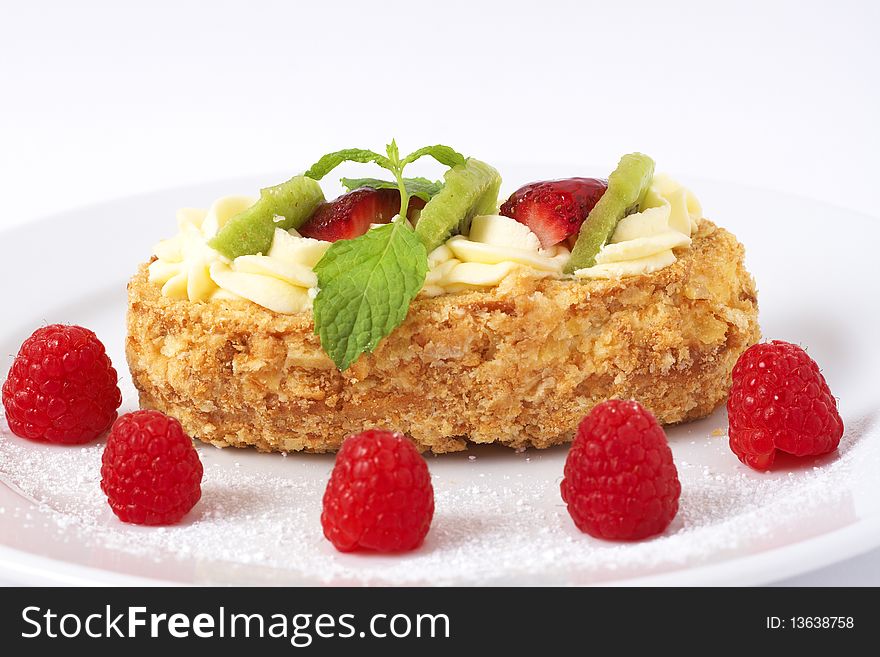 Fruit boat cake with kiwi, strawberries, and raspberries served on a white plate. Fruit boat cake with kiwi, strawberries, and raspberries served on a white plate