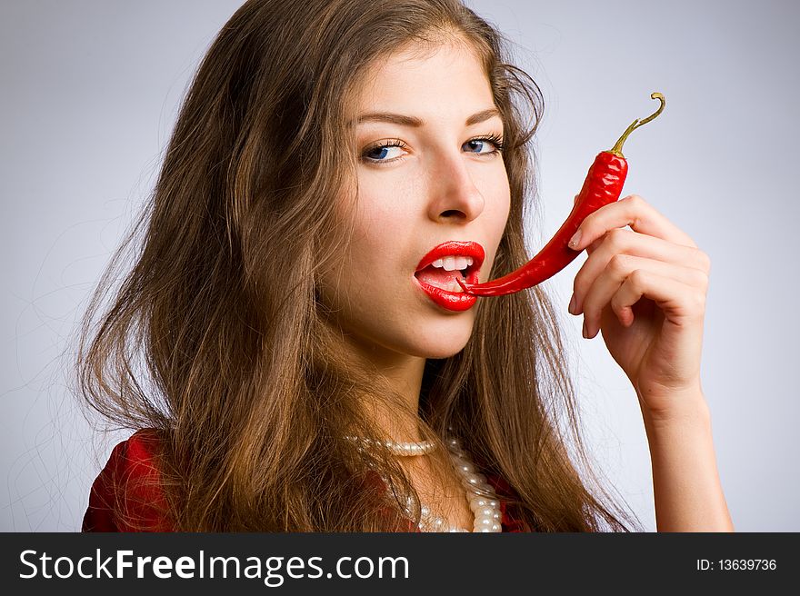 Portrait of a young beautiful girl holding her mouth red chili peppers. Portrait of a young beautiful girl holding her mouth red chili peppers