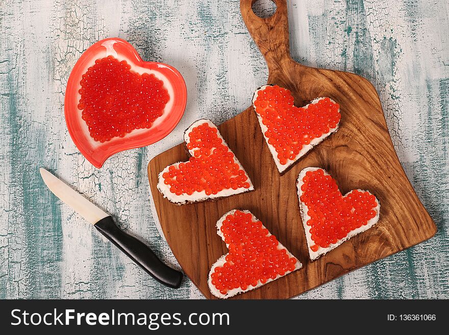 Sandwiches with red caviar and cream cheese in the shape of a heart for Valentine`s Day