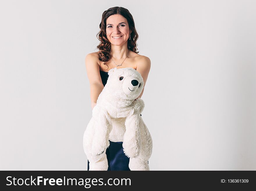Young brunette woman in evening dress with polar bear toy